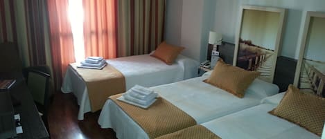 Une chambre d’hôtel avec deux lits, un bureau et une chaise.