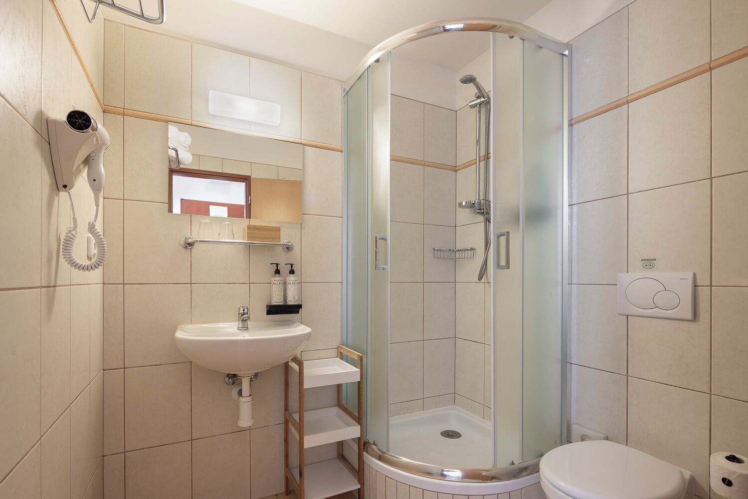 Un bagno compatto con cabina doccia in vetro, lavandino e WC.