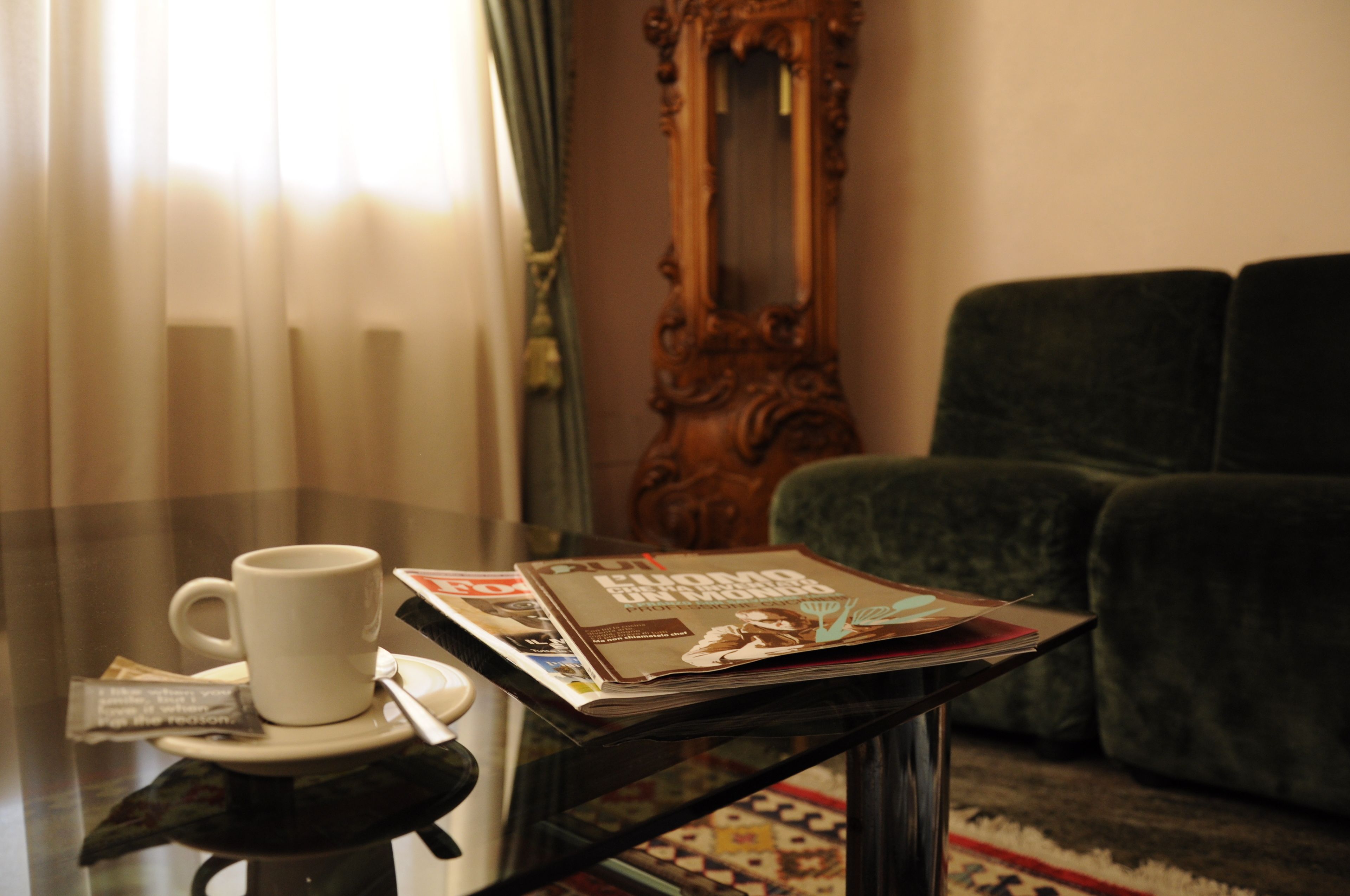 Una mesa con una taza blanca, una revista y un paquete de pañuelos.