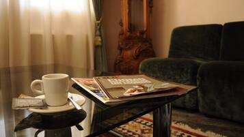 Una mesa con una taza blanca, una revista y un paquete de pañuelos.