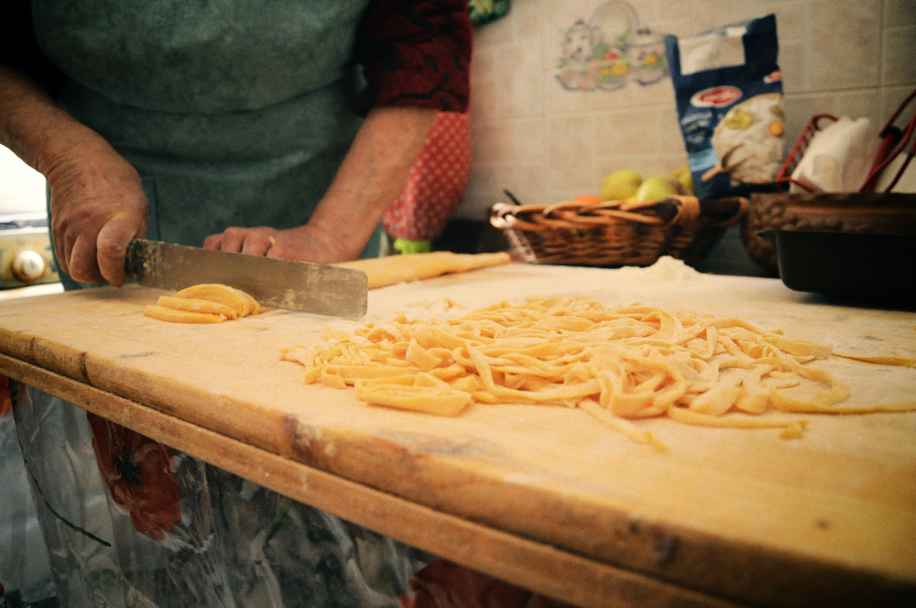 Una persona cortando queso sobre una tabla de madera.