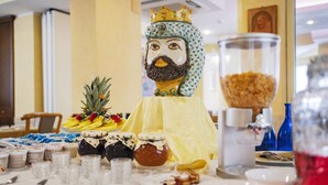 A dining table with a decorative centerpiece, food items, and a glass container. - Hotel Siviglia (Fiuggi)