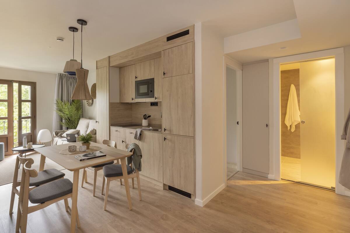 Une cuisine moderne avec des meubles en bois, un four à micro-ondes et un coin repas comprenant une table et des chaises.