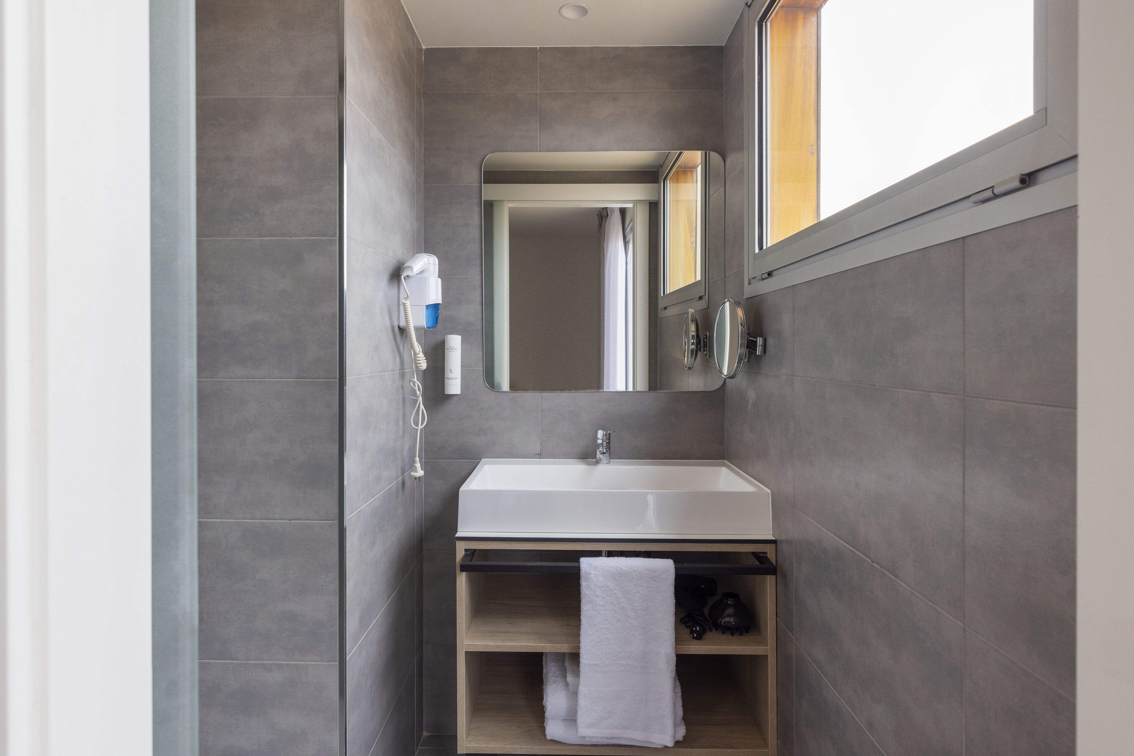 Een moderne badkamer met een wit wastafelmeubel, een spiegel en een handdoekhouder.