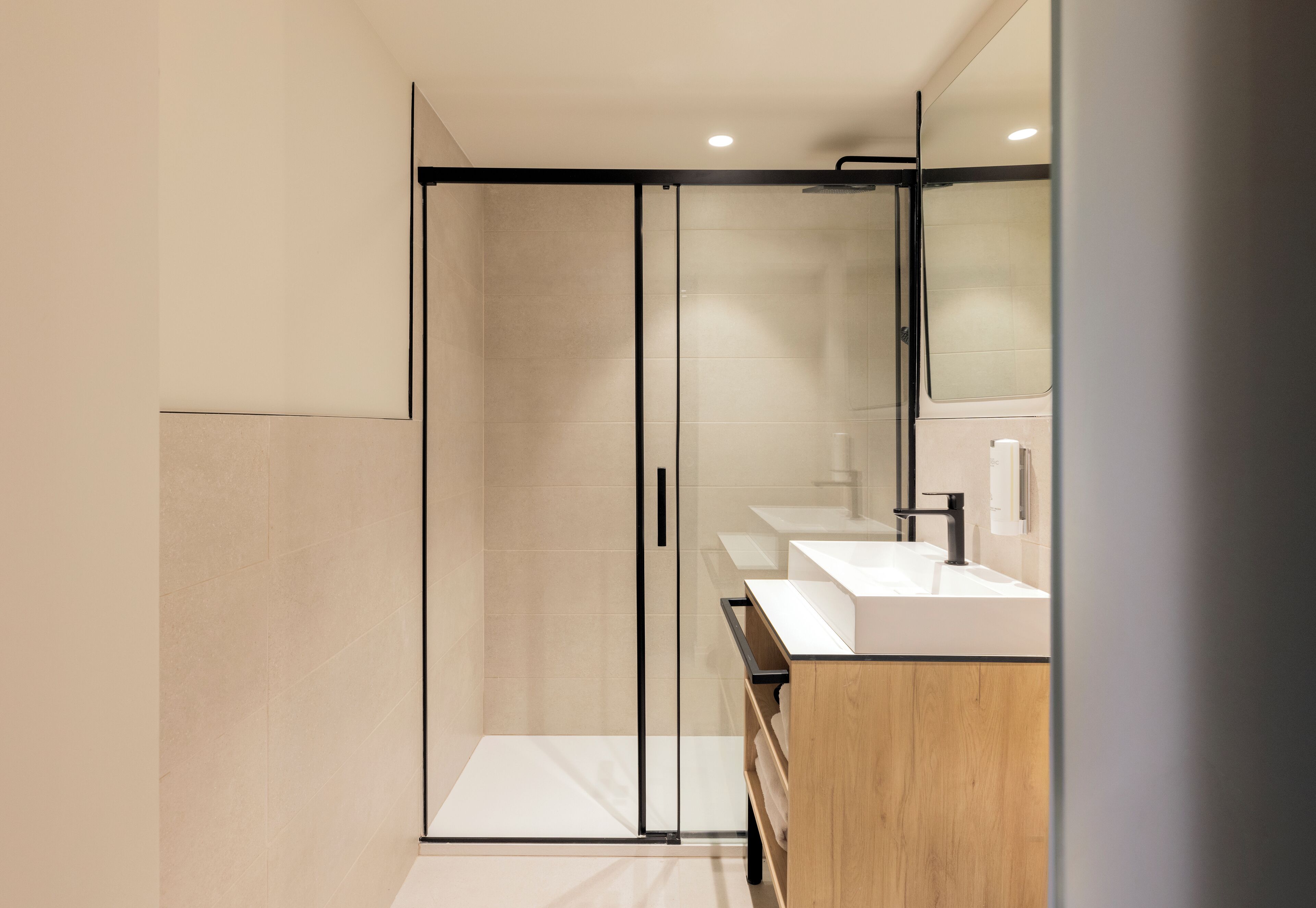 A modern bathroom with a glass-enclosed shower, a wooden vanity, and a large mirror.