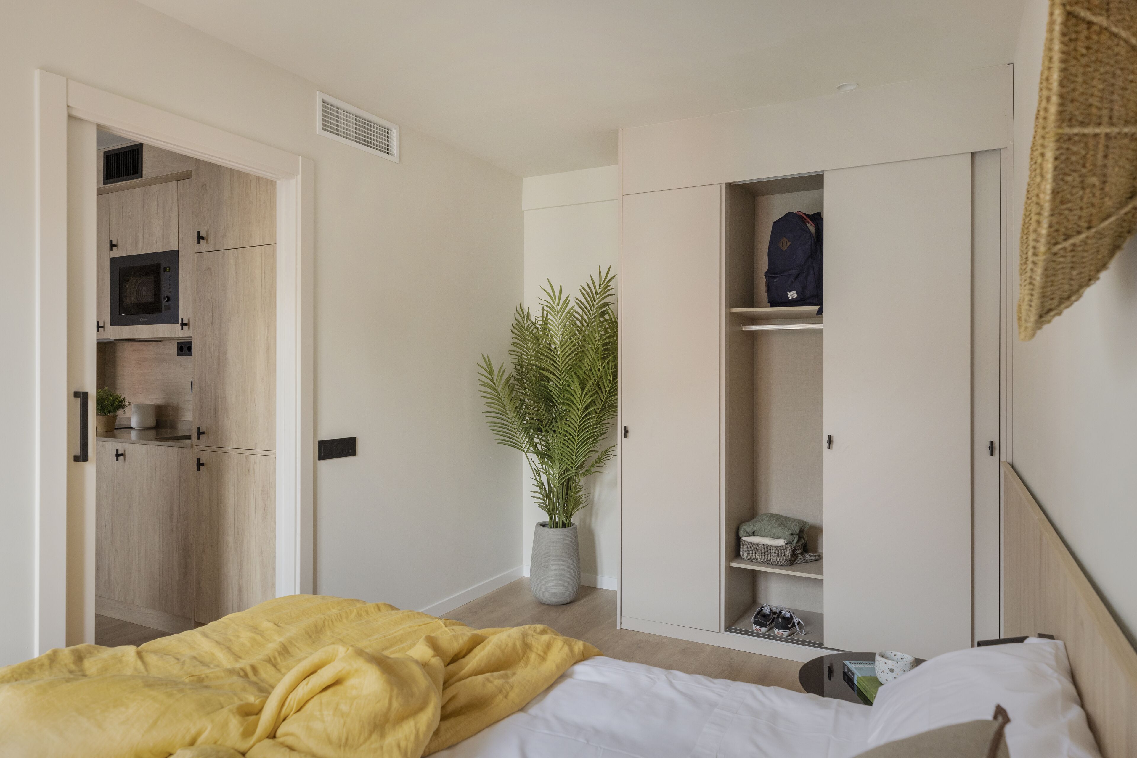 Un dormitorio con cama, armario y una pequeña cocina.