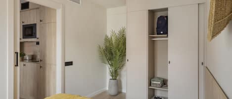 Un dormitorio con cama, armario y una pequeña cocina.