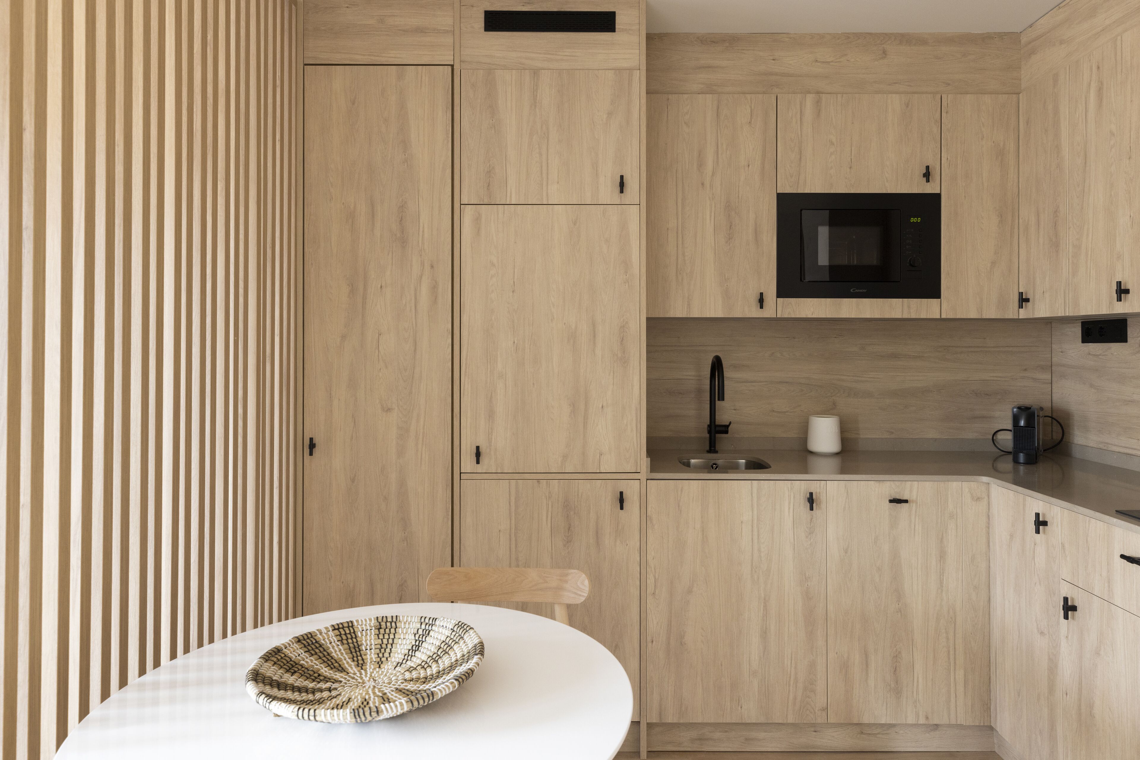 Una cocina moderna con armarios de madera clara, un microondas y una cafetera.