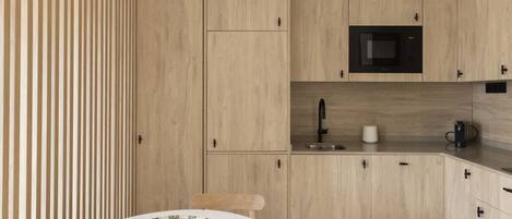 Una cocina moderna con armarios de madera clara, un microondas y una cafetera.
