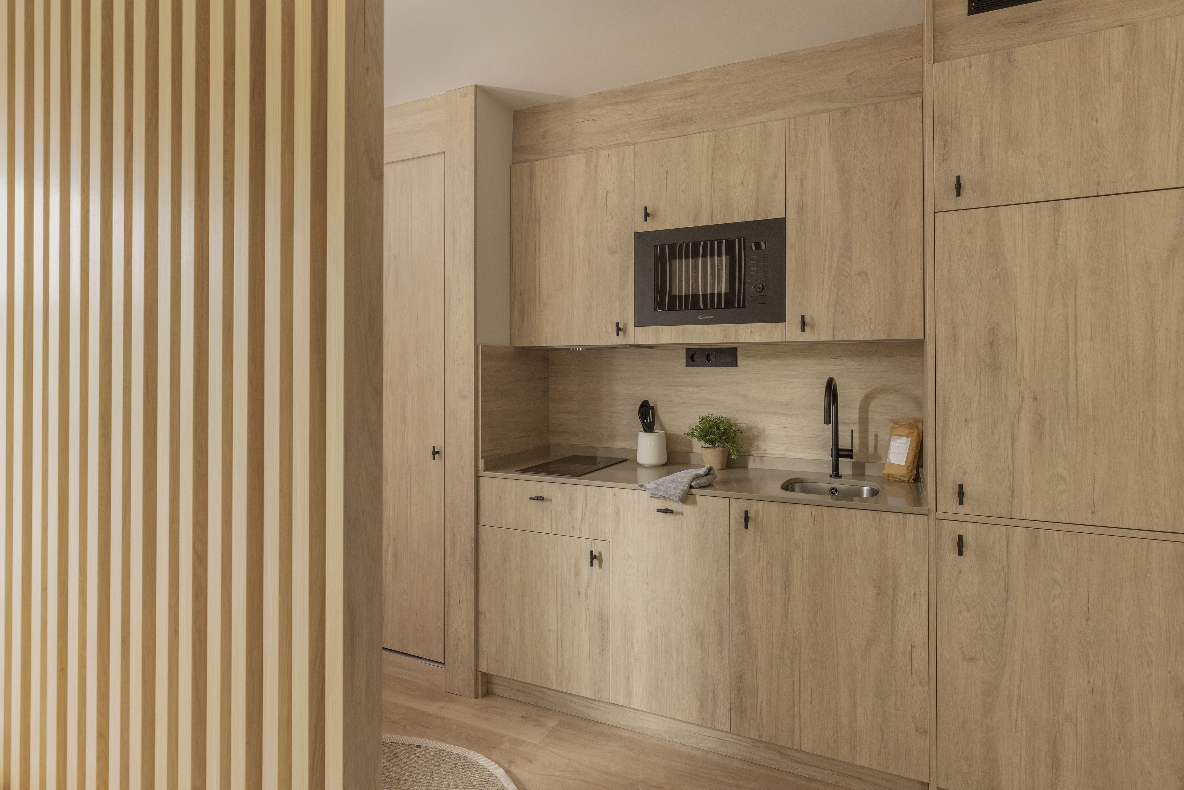 A modern kitchen with wooden cabinets, a built-in microwave, and a sink.