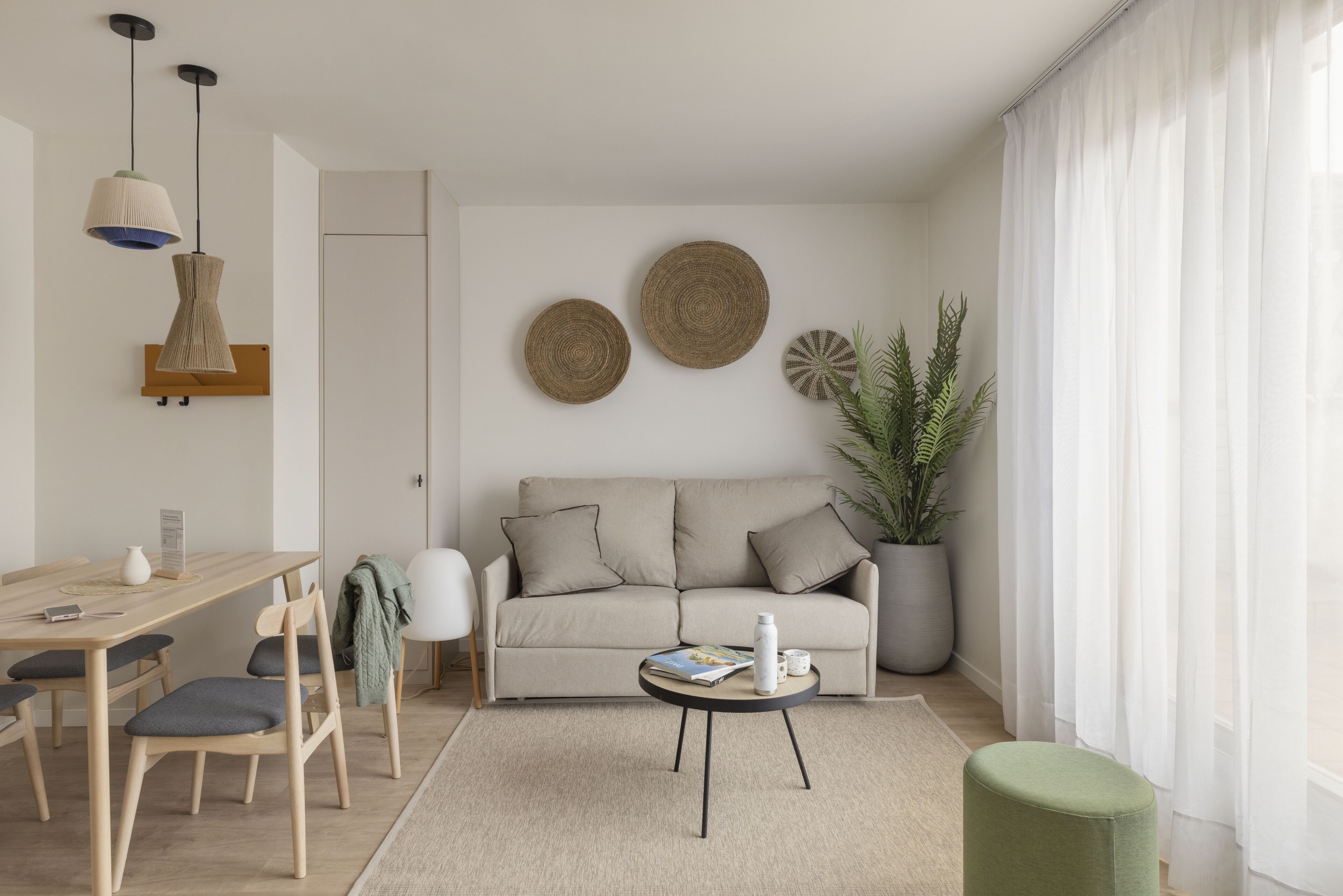 A modern living room with a sofa, a coffee table, and a dining area with chairs and a table.