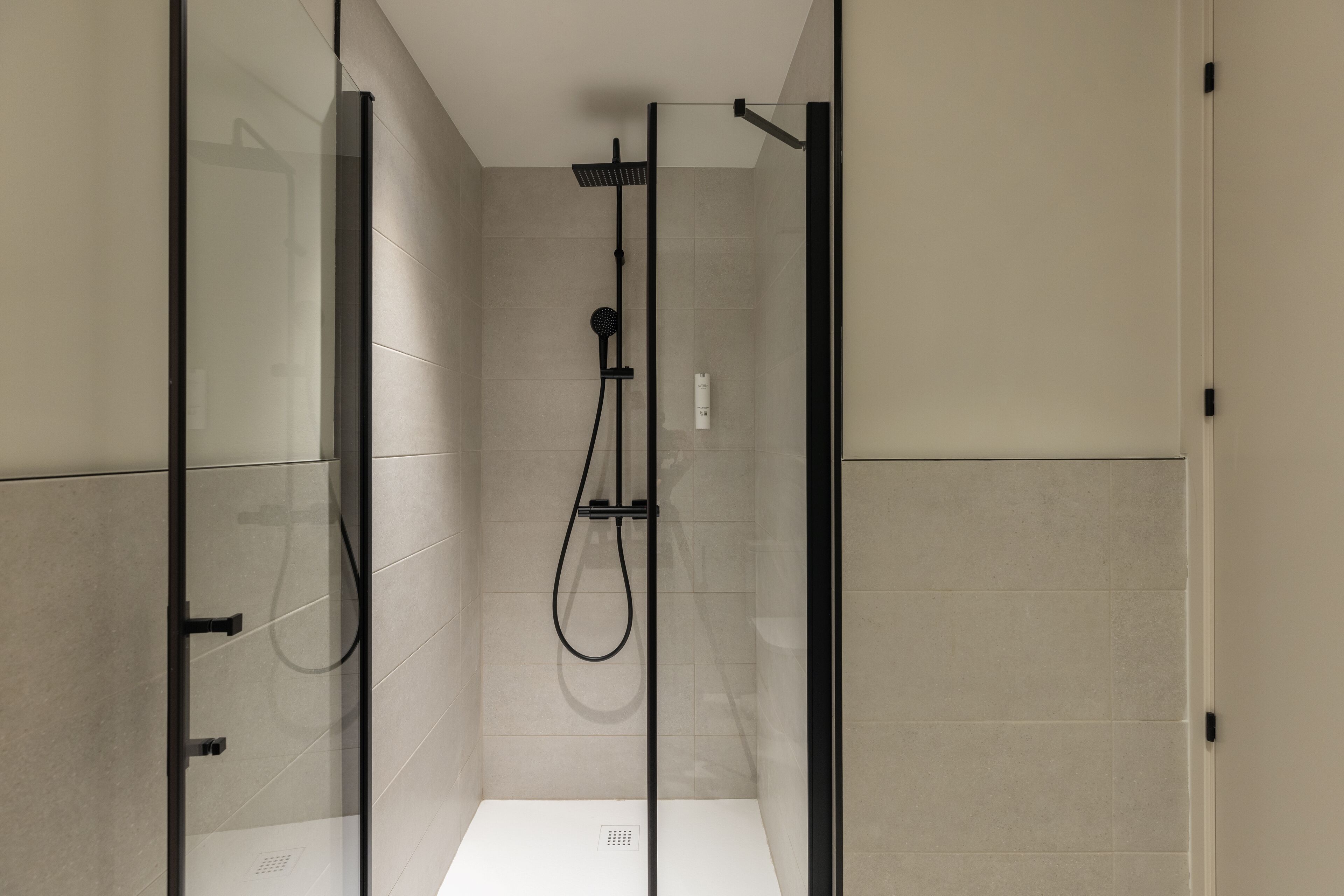 Eine moderne Dusche mit Glasabtrennung, einer Handbrause und einem wandmontierten Bedienfeld.