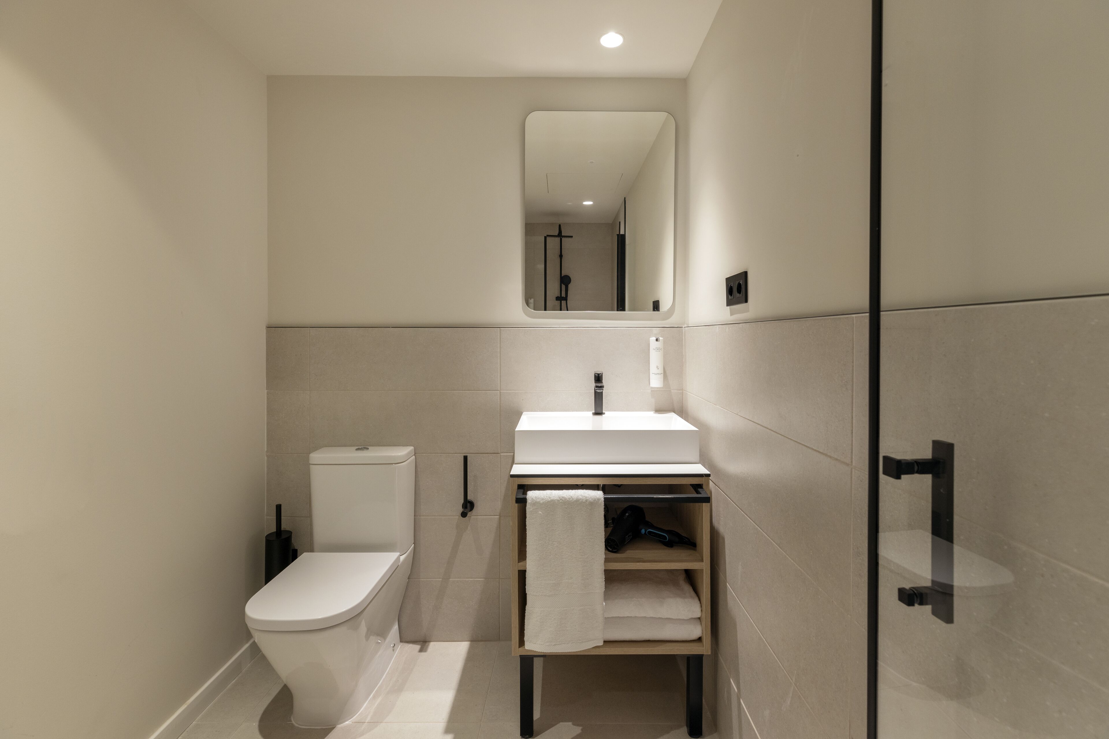 A modern bathroom with a toilet, sink, and mirror.