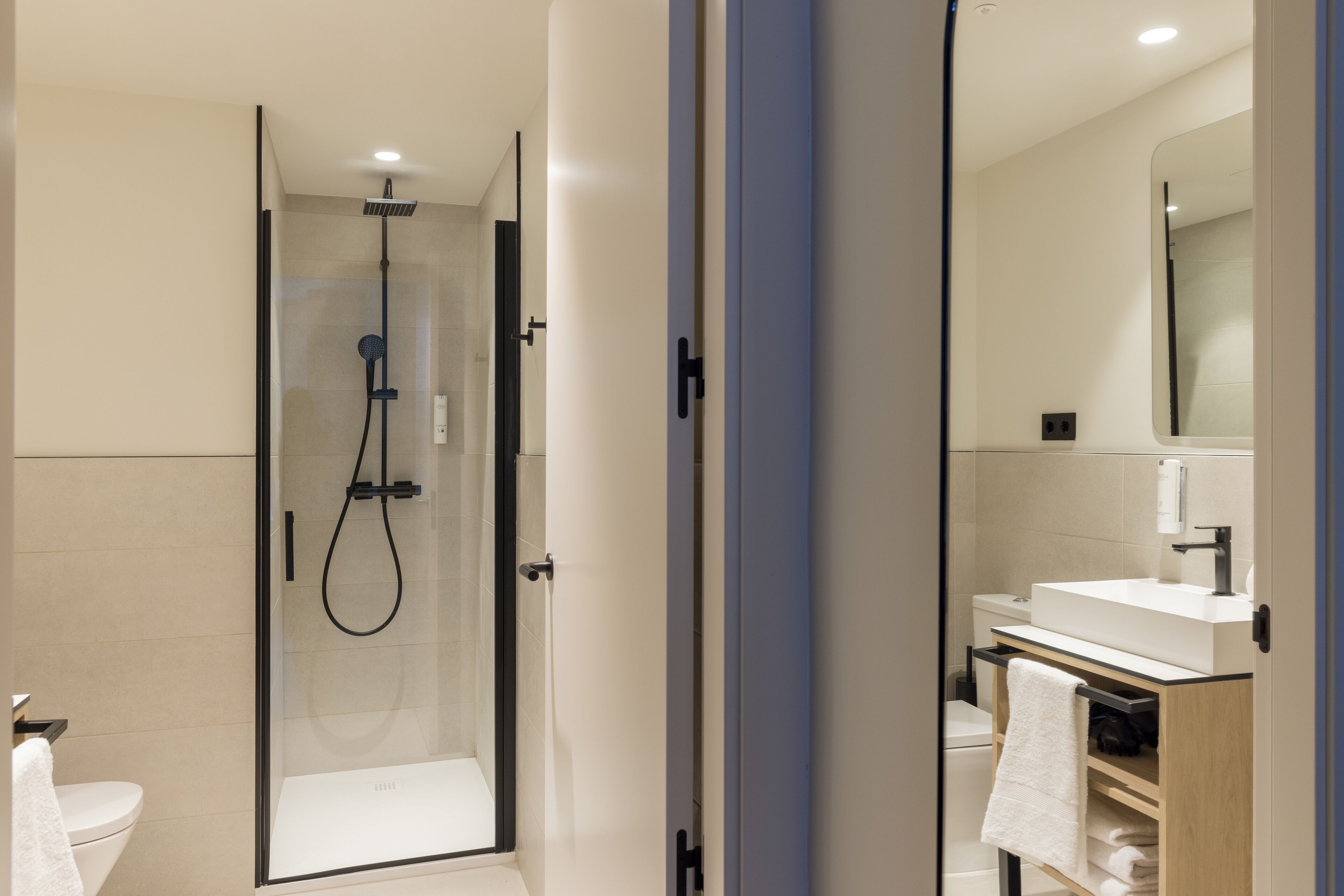 Un bagno moderno con doccia vetrata, lavandino bianco e specchio sopra il lavandino.