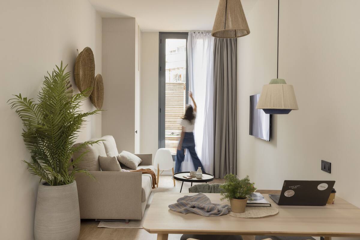 Un salon moderne avec un canapé, une table basse, un ordinateur portable et une plante en pot.