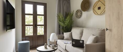 A modern living room with a sofa, a coffee table, a laptop, and a plant.