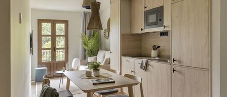 A modern kitchen with wooden cabinets, a built-in microwave, and a dining area with a table and chairs.