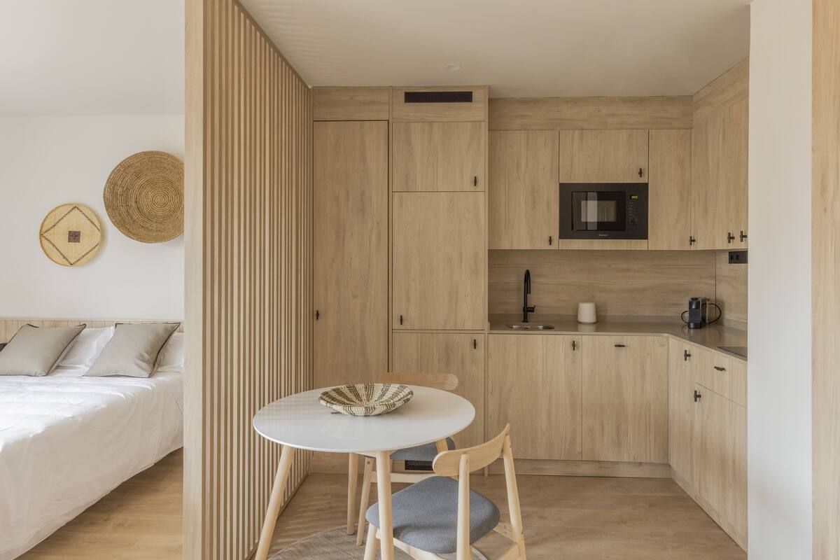 Une cuisine compacte avec des meubles en bois, un four à micro-ondes et un petit coin repas comprenant une table ronde et des chaises.
