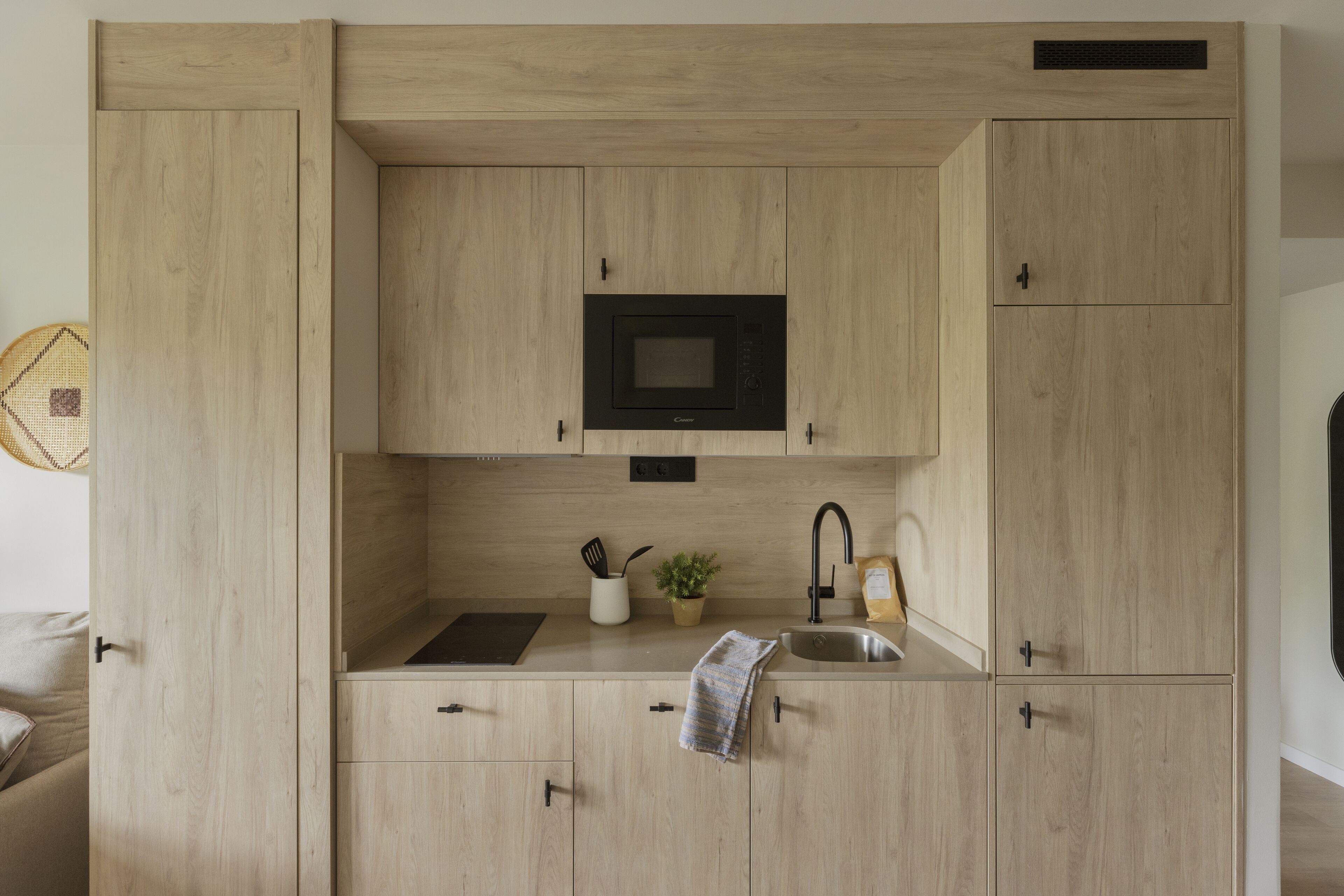 A compact kitchen with wooden cabinets, a built-in microwave, a sink, and a small countertop area.