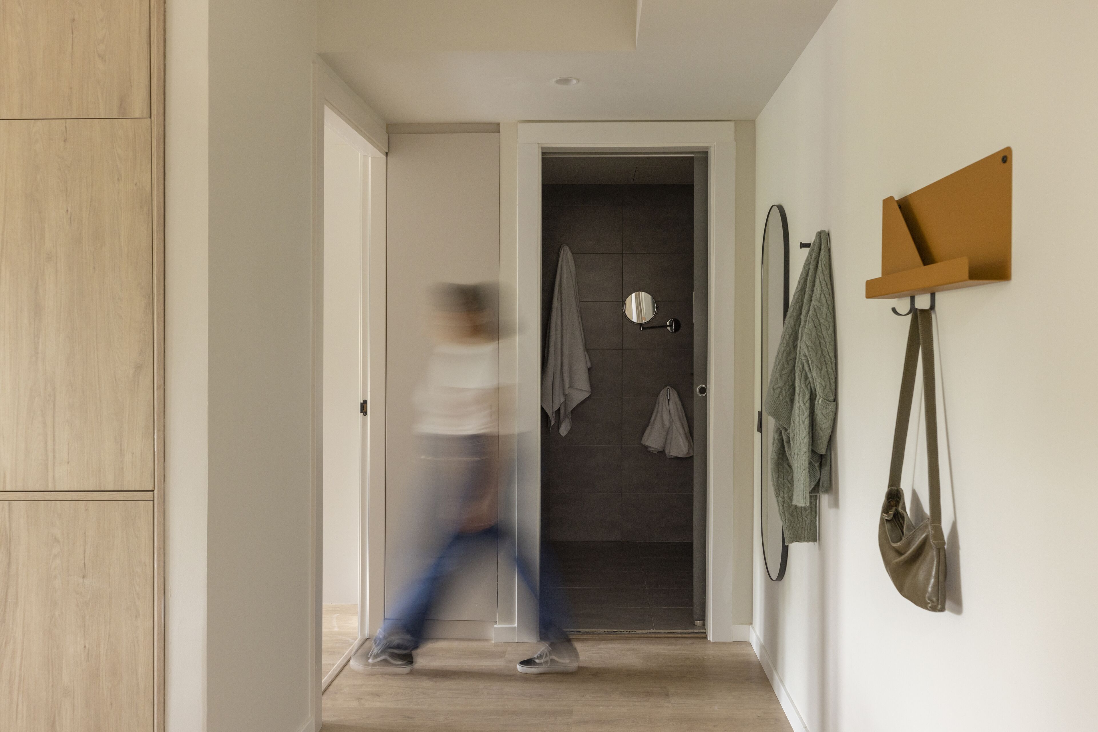 A hallway with a wooden wardrobe, a mirror, and a coat rack with bags.