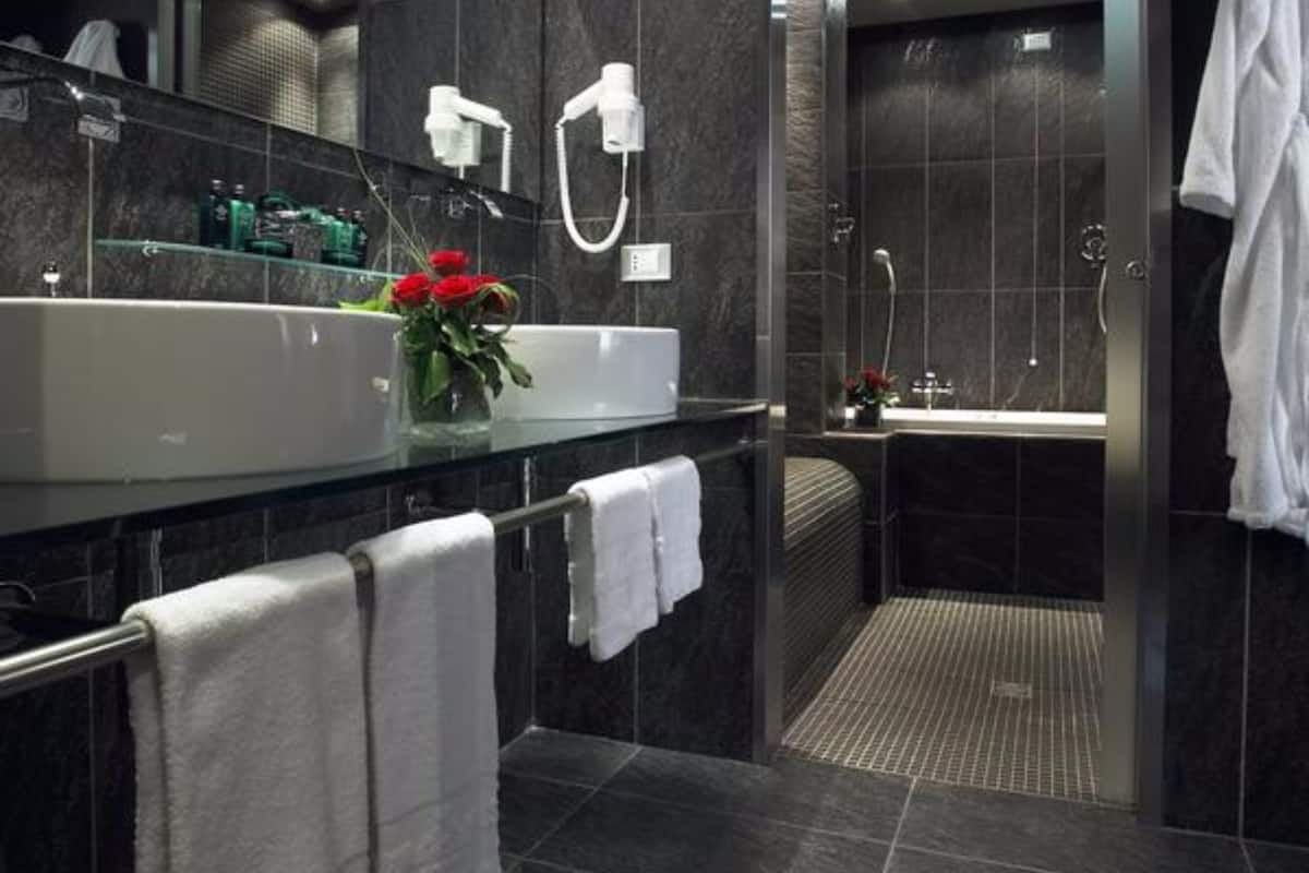 A modern bathroom with a large sink, mirror, and shower area.