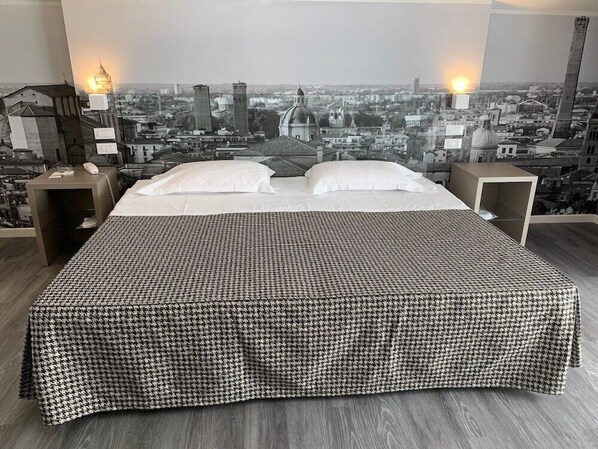 A hotel room with a large bed, two bedside tables, and a cityscape view. - Savoia Hotel Regency (Bologna)