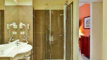 Un baño moderno con ducha de vidrio, lavamanos con espejo y teléfono.