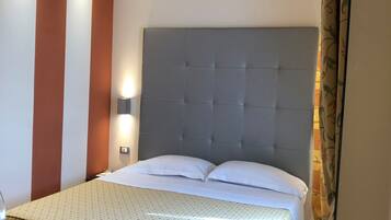 Een net opgemaakt bed met een bedspreide met een patroon, een gestuwd hoofdeinde en een muur met verticale strepen.