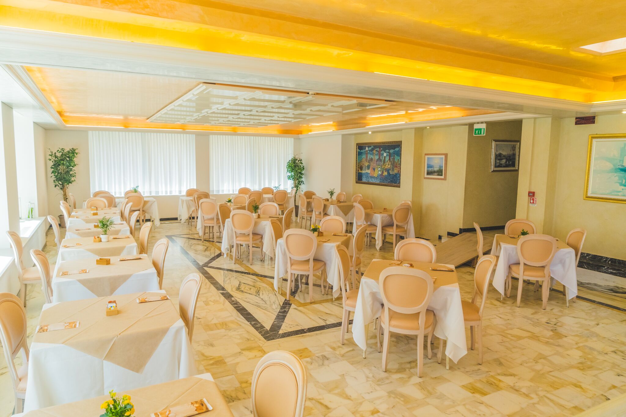 A banquet hall with multiple tables and chairs, a patterned floor, and a ceiling with recessed lighting.