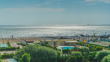 A coastal hotel with a pool, beach access, and a view of the sea.