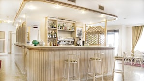 A bar area with wooden paneling, white bar stools, and shelves stocked with bottles.