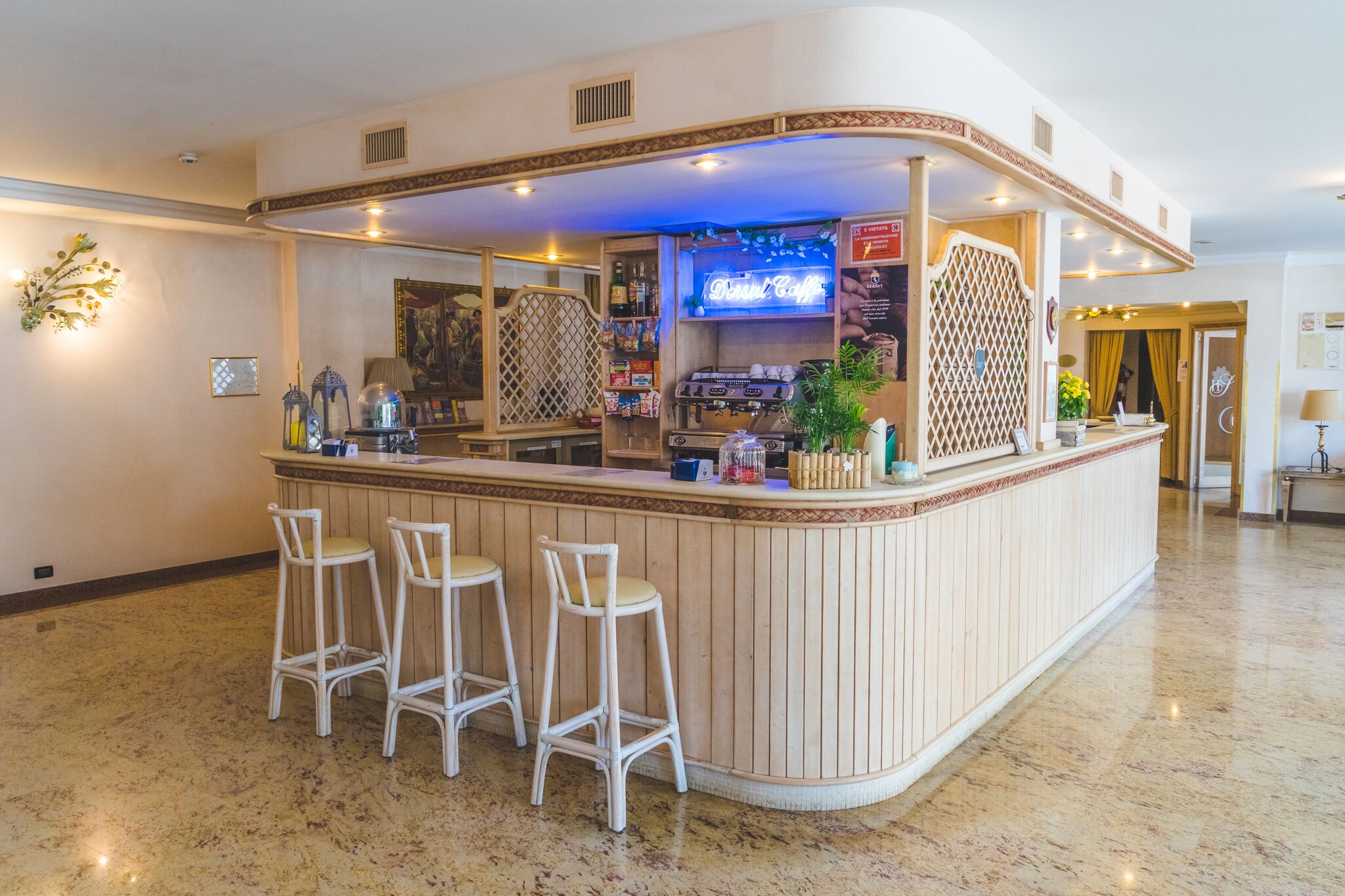 Un espace bar doté d’un comptoir incurvé, de trois tabourets de bar blancs et d’un écran de télévision.