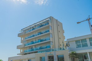 A multi-story hotel with balconies, a crane in the background, and a clear sky. - Hotel Sole (Chioggia)
