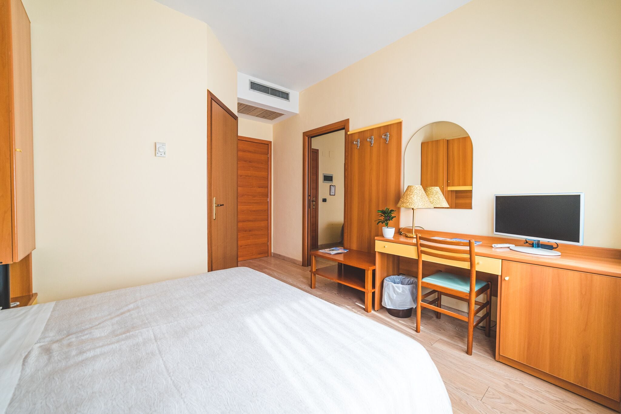 Una camera da letto con un letto, una scrivania con una sedia, una televisione e un armadio.