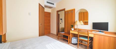 Une chambre à coucher comprenant un lit, un bureau avec une chaise, une télévision et une armoire.