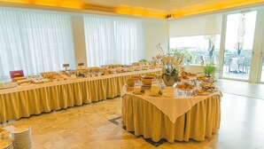 A buffet setup with various food items and a table with plates and cups.