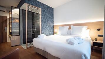 A modern hotel room with a large bed, a walk-in closet, and a patterned wall.