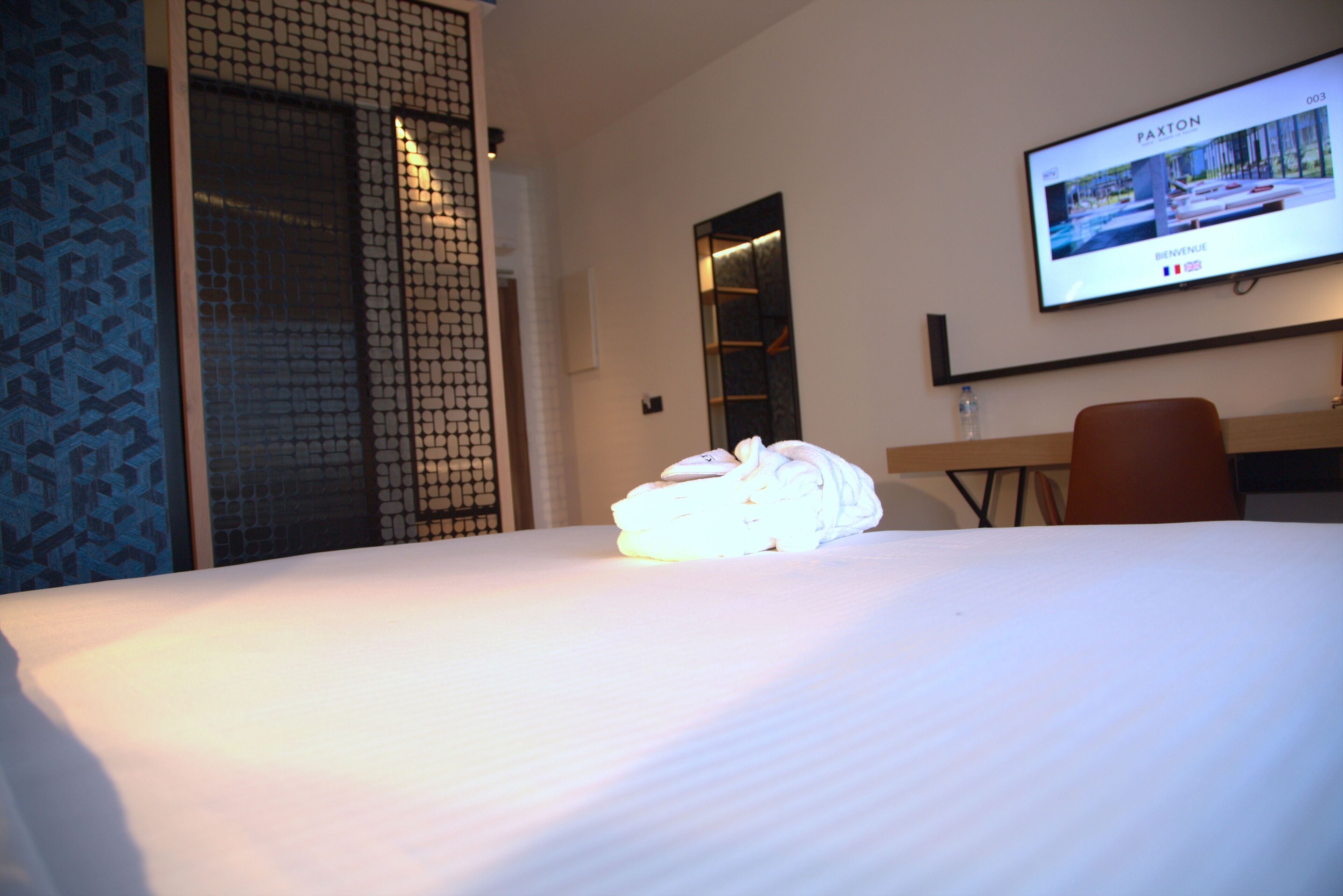 Een hotelkamer met een net opgemaakt bed, een televisie aan de muur en een bureau met een stoel.