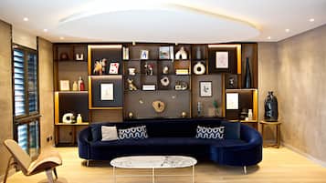 A modern living room with a dark blue sofa, a round coffee table, and a built-in shelving unit with various decorative items.