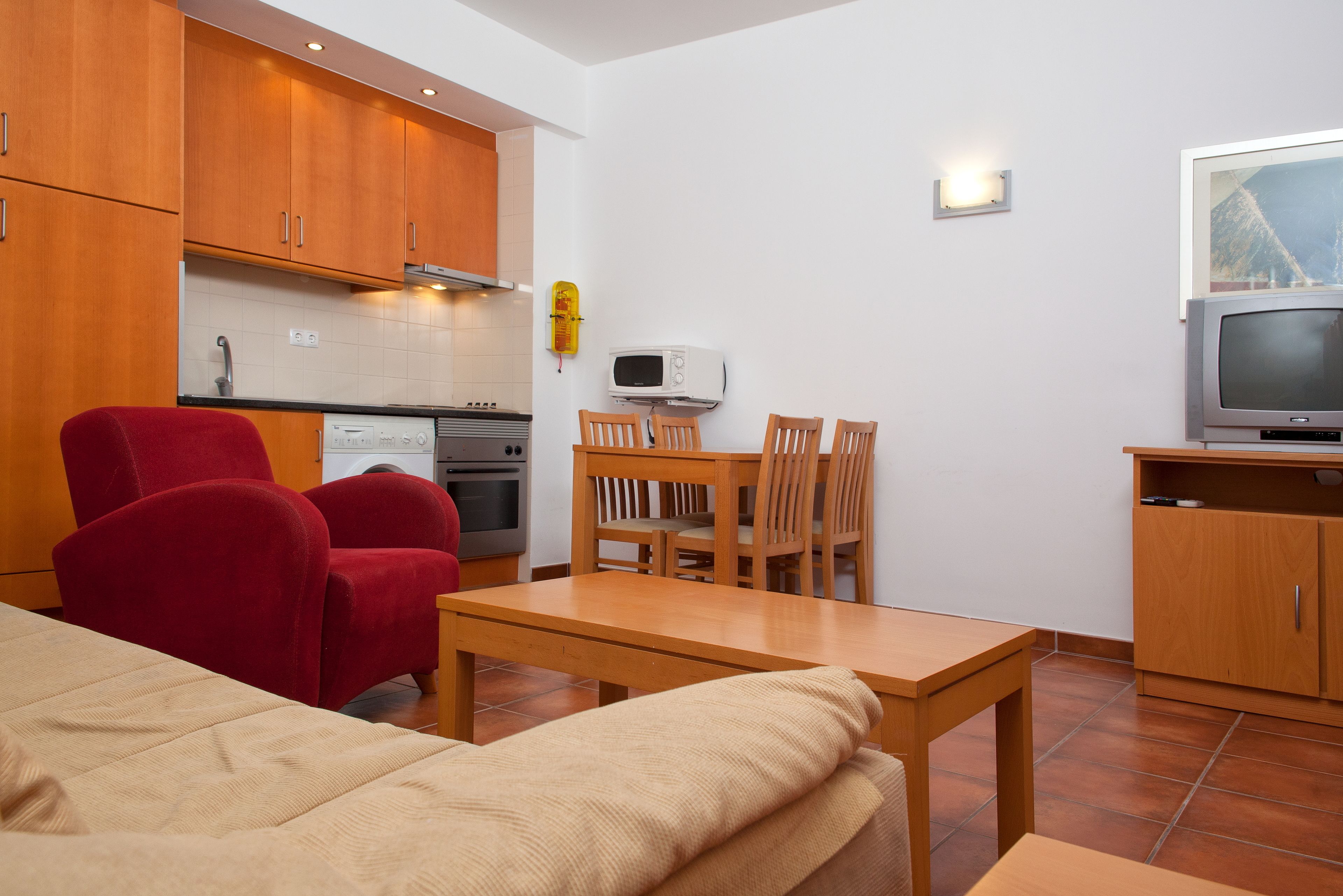 Een knus woongedeelte met een kitchenette, een eethoek en een televisie.