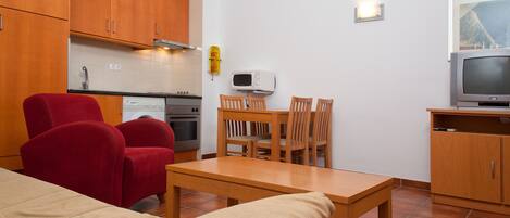 A compact living space with a kitchenette, a dining area, and a TV.