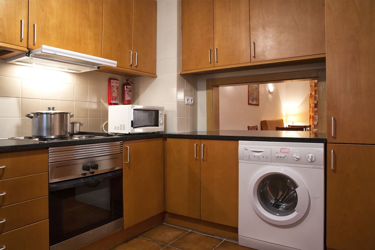 A kitchen with wooden cabinets, a stainless steel oven, a microwave, and a front-loading washing machine.