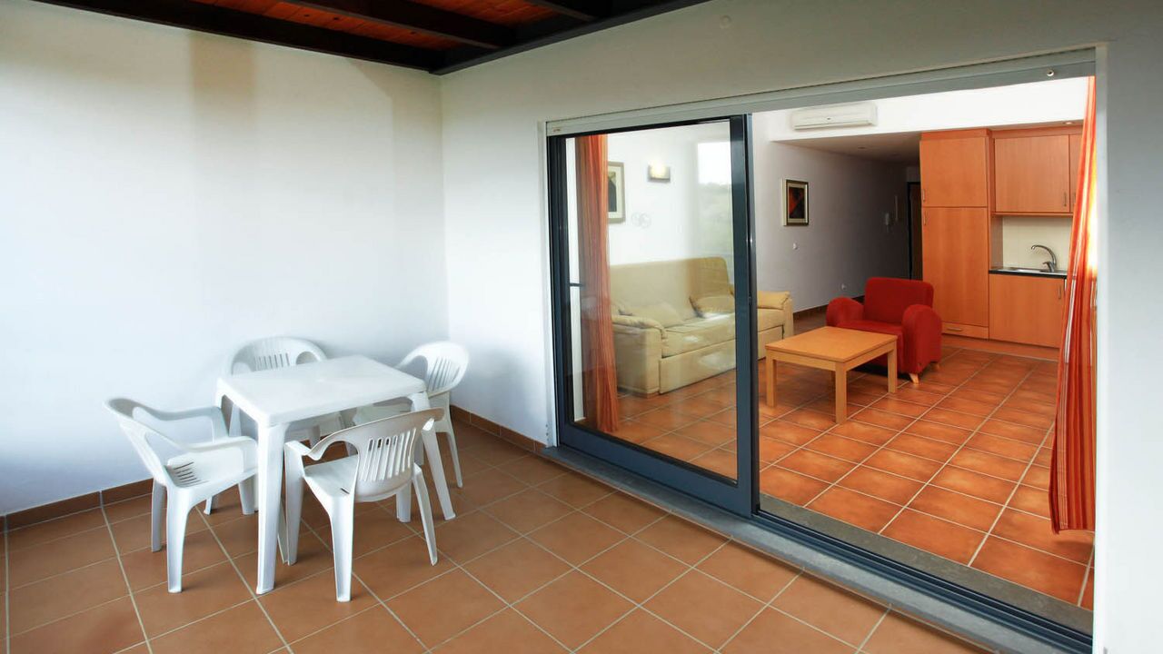 A room with a sliding glass door leading to a living area, a small kitchen, and a dining area with a table and chairs.