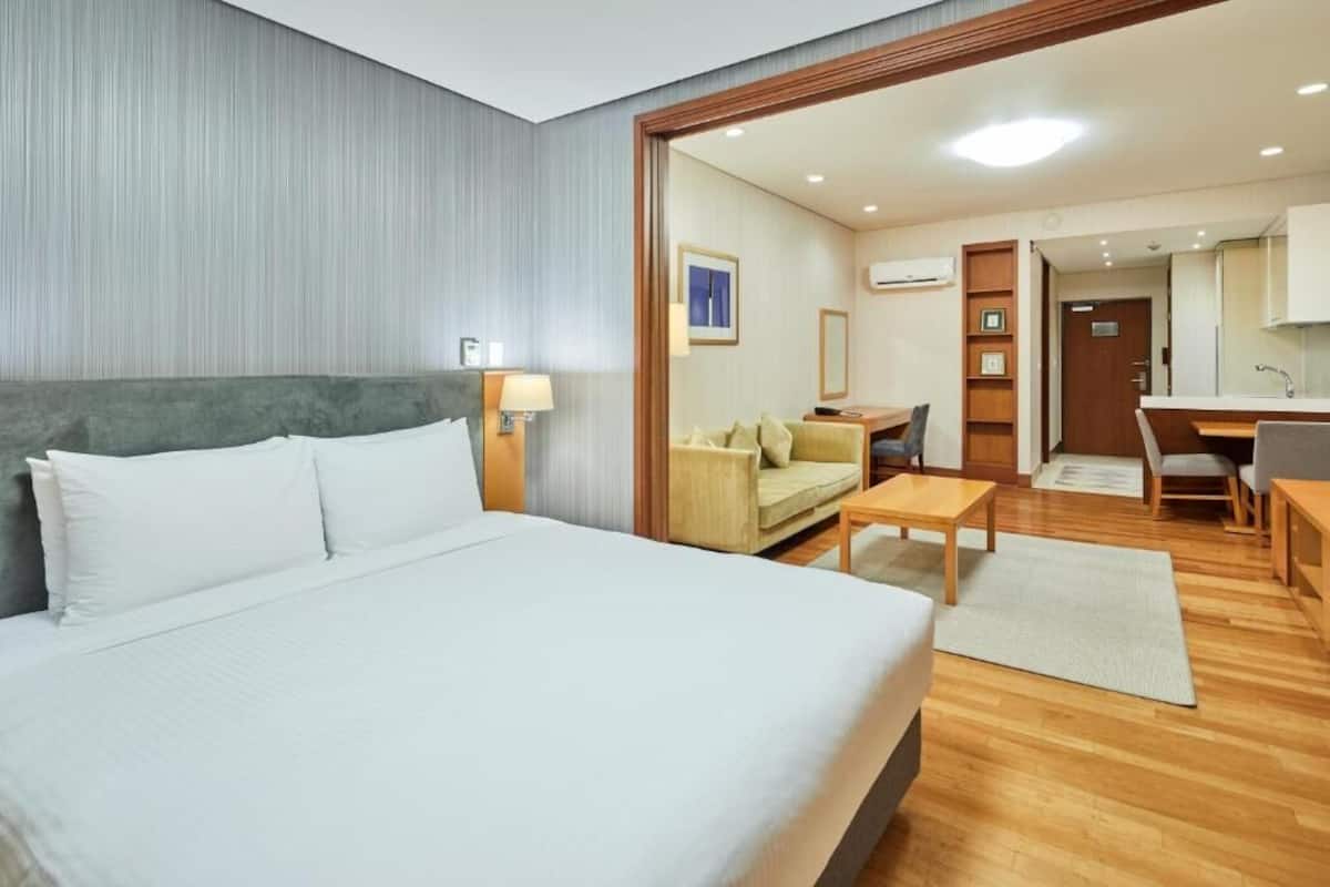 A hotel room with a bed, a desk, a sofa, and a kitchenette.