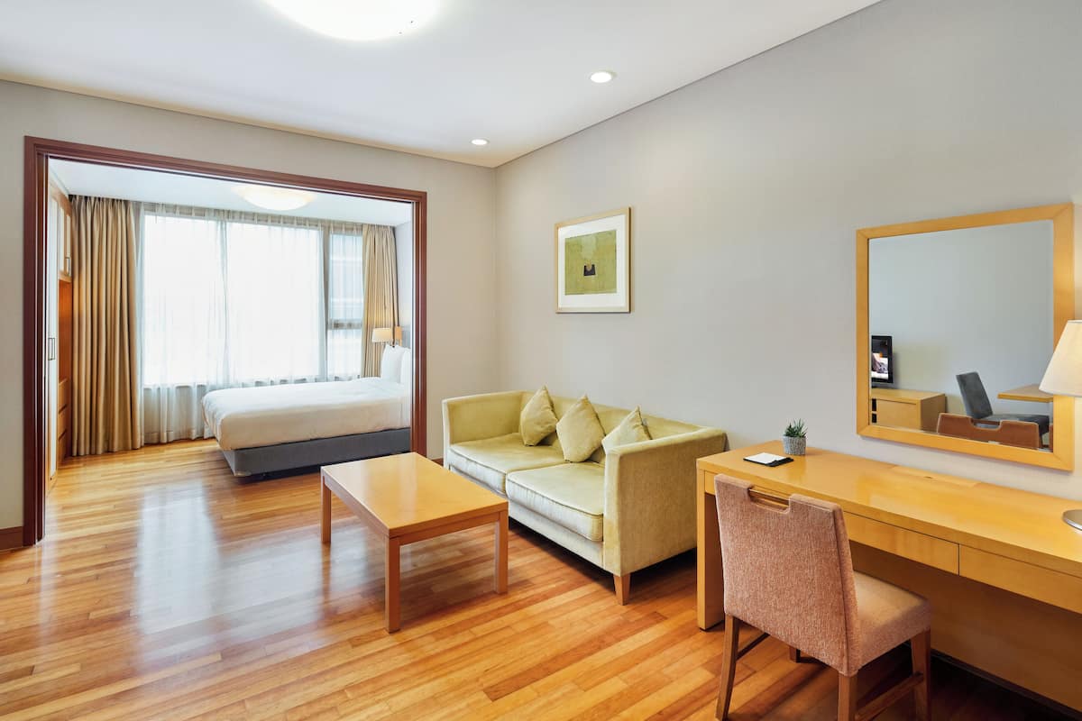Una habitación de hotel con cama, sofá, escritorio y una silla.