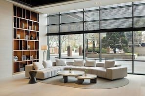 A modern living room with a sectional sofa, two round coffee tables, and a large bookshelf. - Somerset Palace Seoul (Seoul)