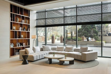 A modern living room with a sectional sofa, two round coffee tables, and a large bookshelf.. Somerset Palace Seoul
