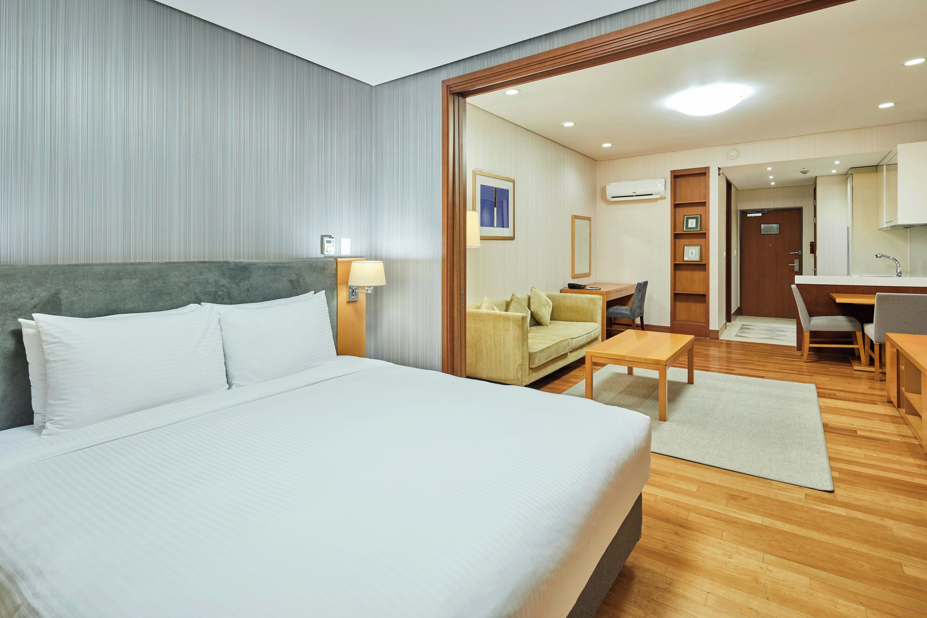 Una habitación de hotel con una cama grande, un escritorio, un sofá y una kitchenette.