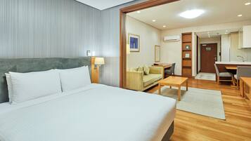 Una habitación de hotel con una cama grande, un escritorio, un sofá y una kitchenette.