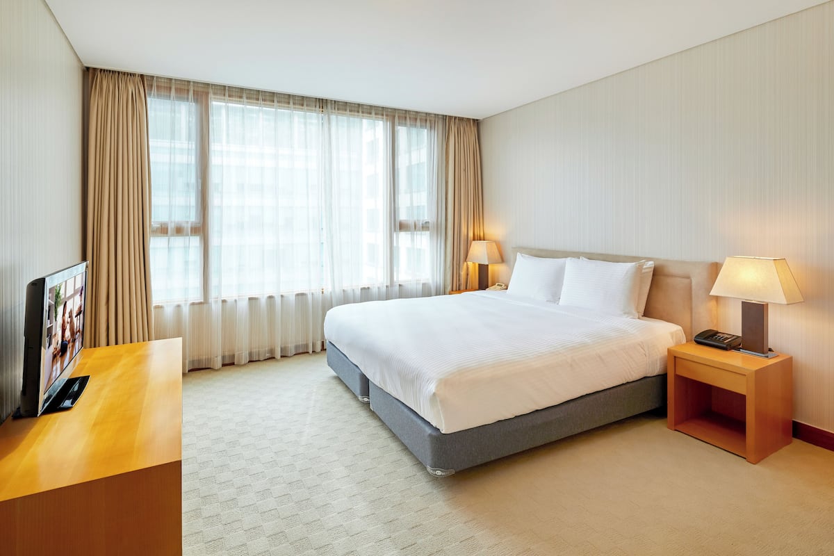 Habitación de hotel con una cama grande, dos lámparas de noche, un televisor de pantalla plana y una mesita de noche de madera.